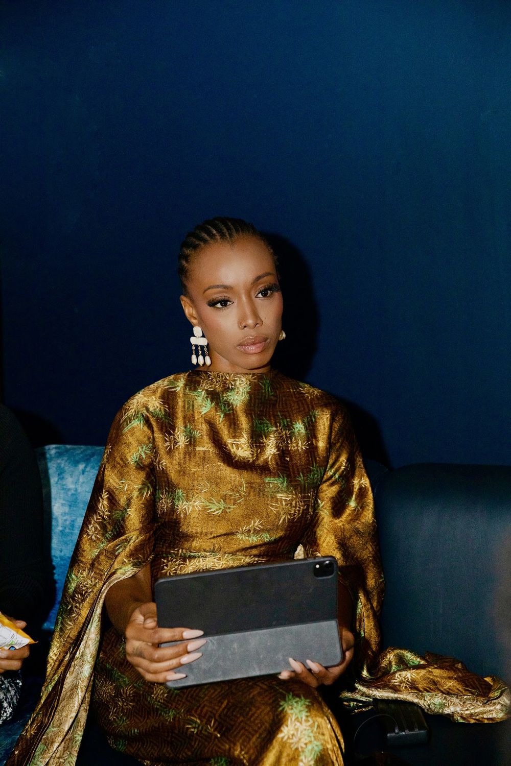 Paige Lewin in a gold dress, holding a tablet