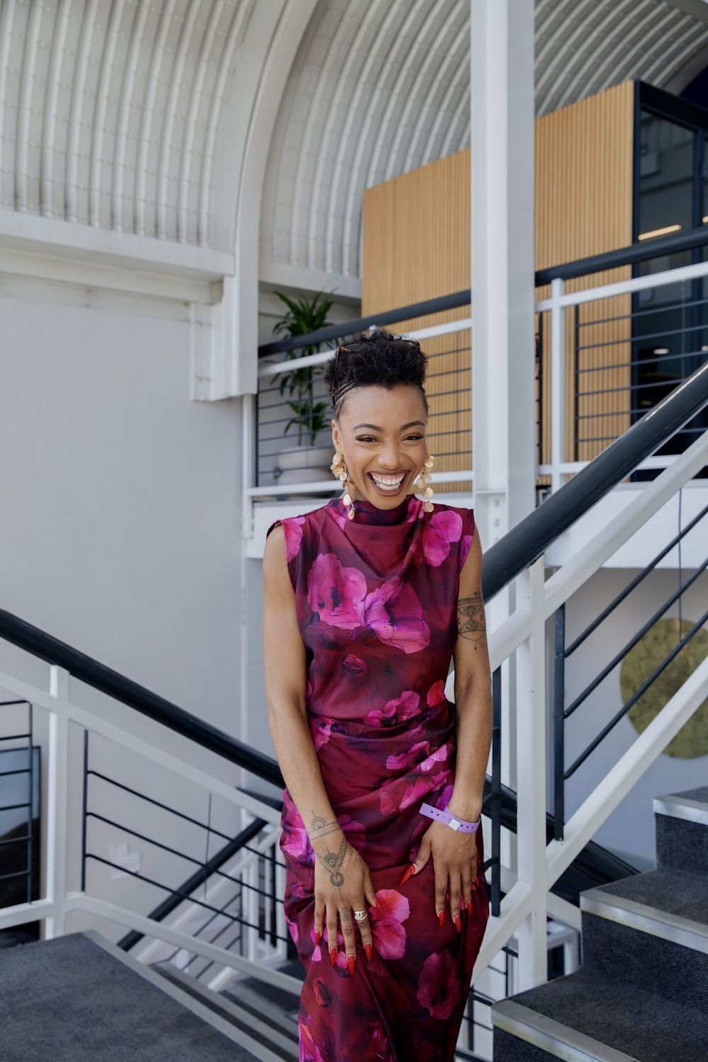 Paige Lewin smiling on a staircase in a raspberry dress